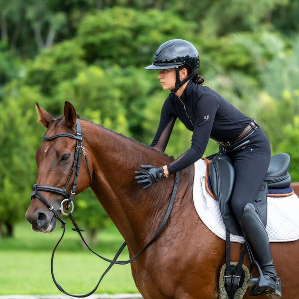 Woman riding a brown horse in an outdoor setting with greenery.