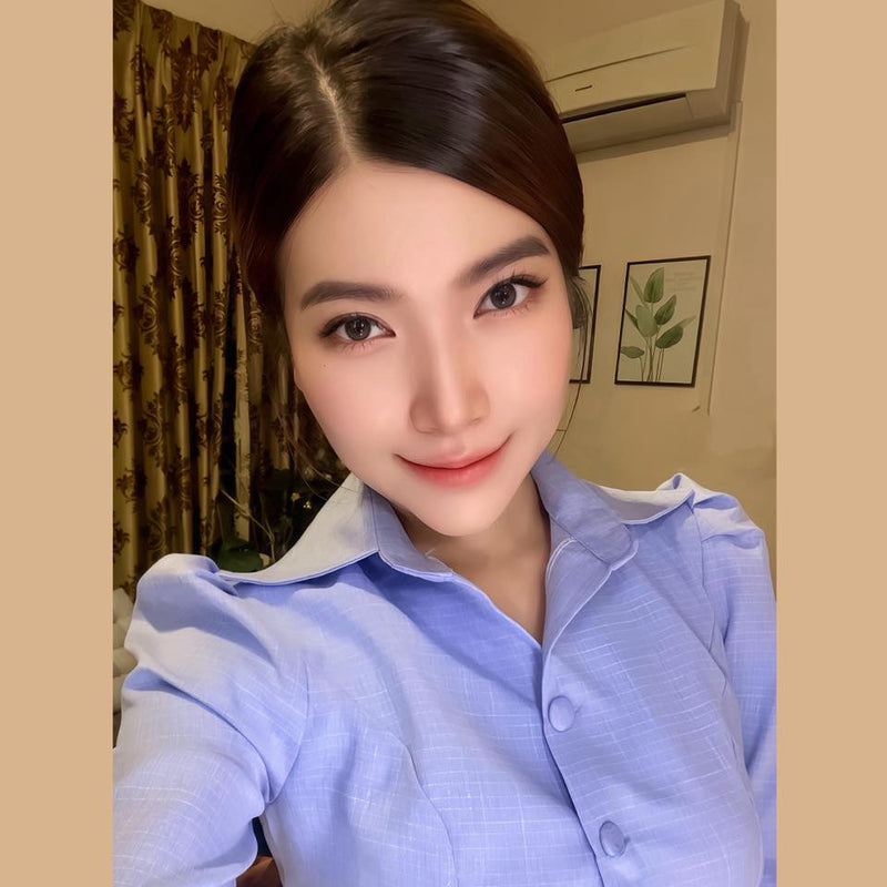 Person wearing a light blue shirt indoors with a neutral background