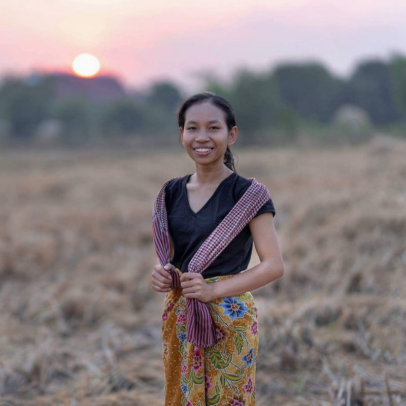 Woman standing in a field with a sunset in the background