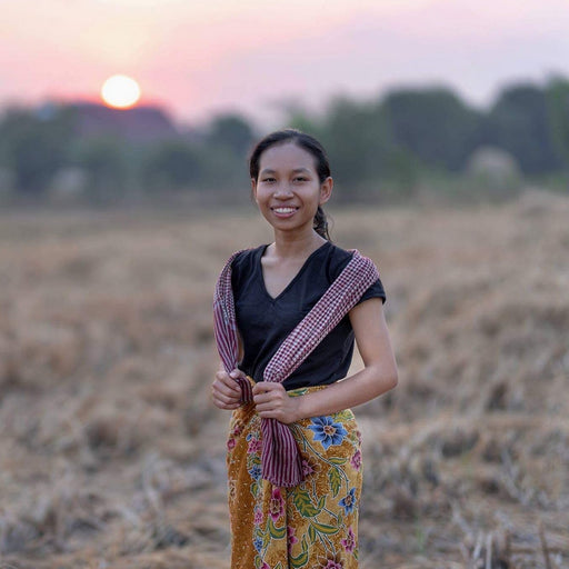 Woman standing in a field with a sunset in the background
