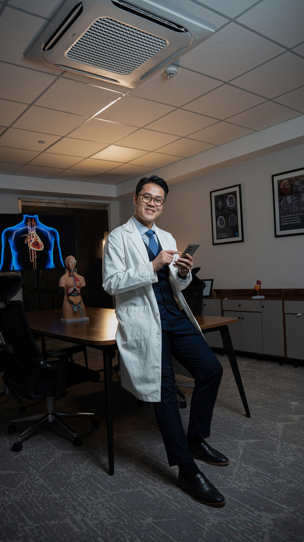 Doctor in a white coat holding a smartphone in an office setting.