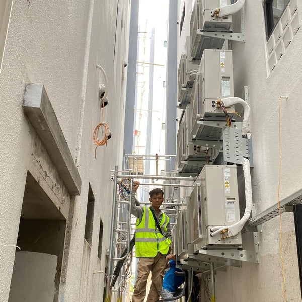 Person in a high-visibility vest working on an industrial setup with air conditioning units.