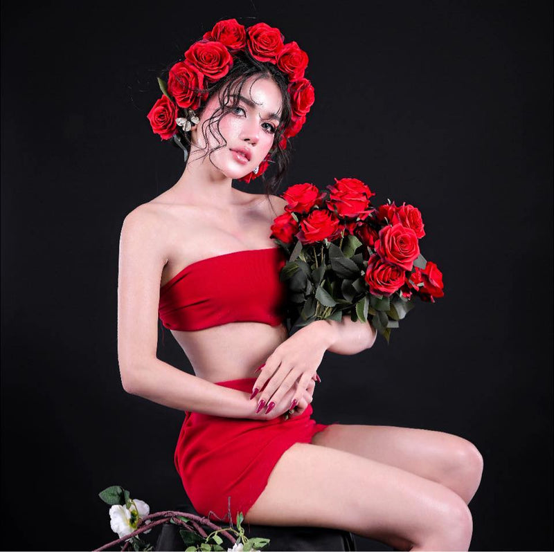 Woman in a red outfit holding red roses against a black background