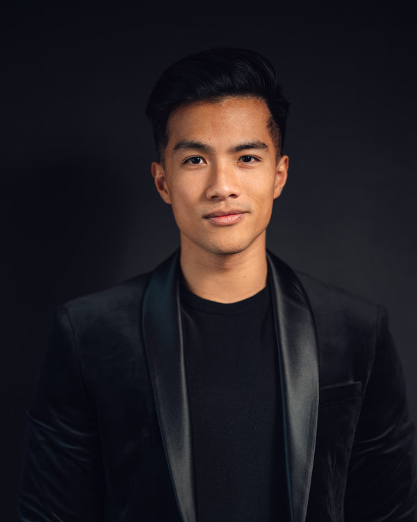 Man wearing a black suit with a dark background