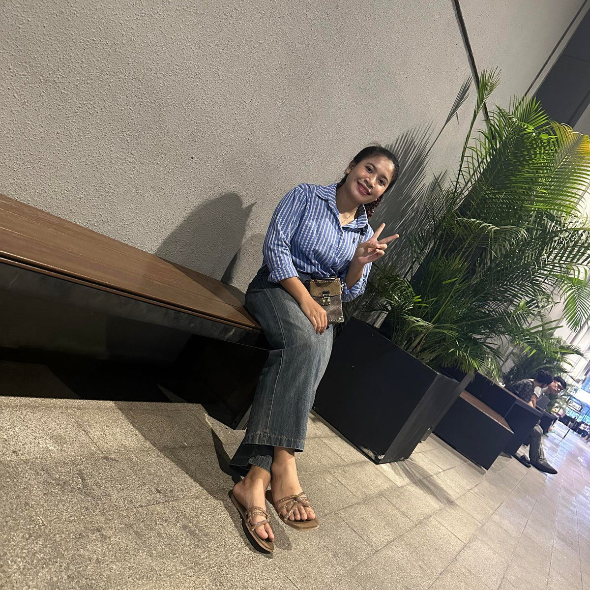 Woman sitting on a bench with a plant in the background