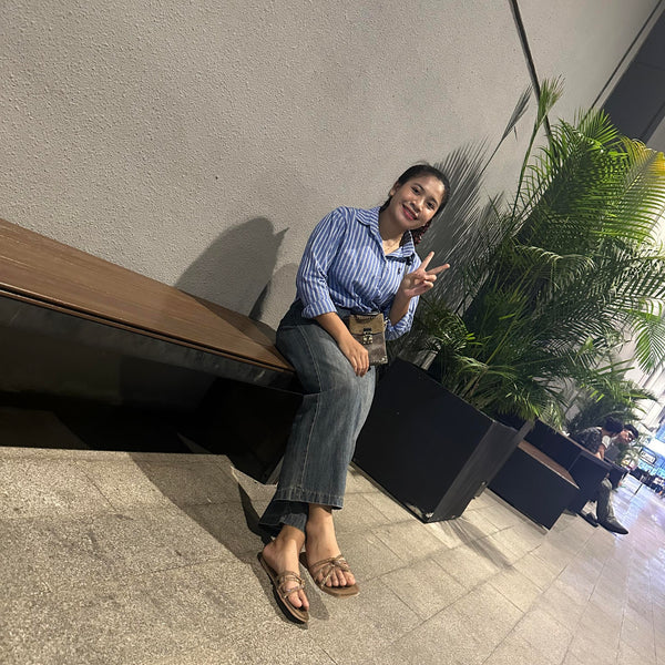 Woman sitting on a bench with a plant in the background