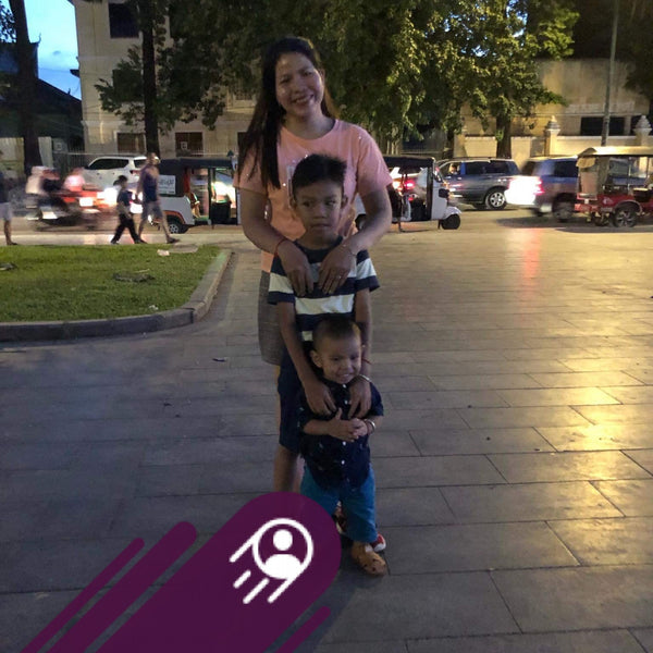 Woman with two children on a city street at night