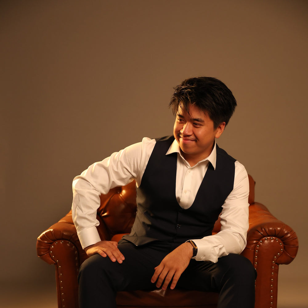 Man sitting on a brown leather chair against a plain background