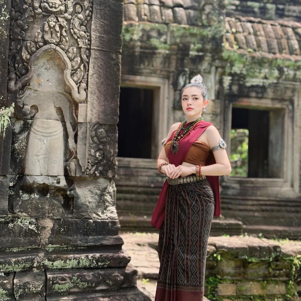 Woman in traditional attire standing in front of an ancient temple.