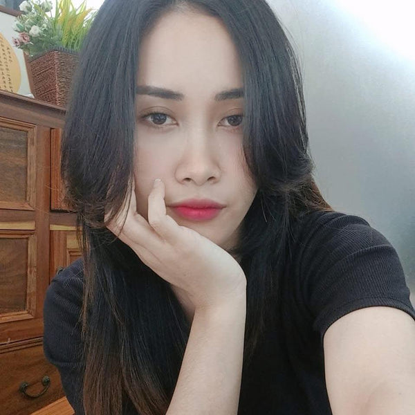 Woman with dark hair and red lipstick posing indoors