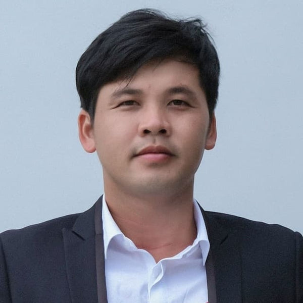 Man wearing a dark suit and white shirt against a light gray background