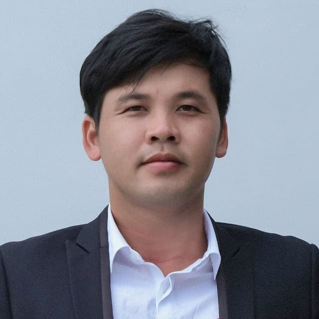 Man wearing a dark suit and white shirt against a light gray background