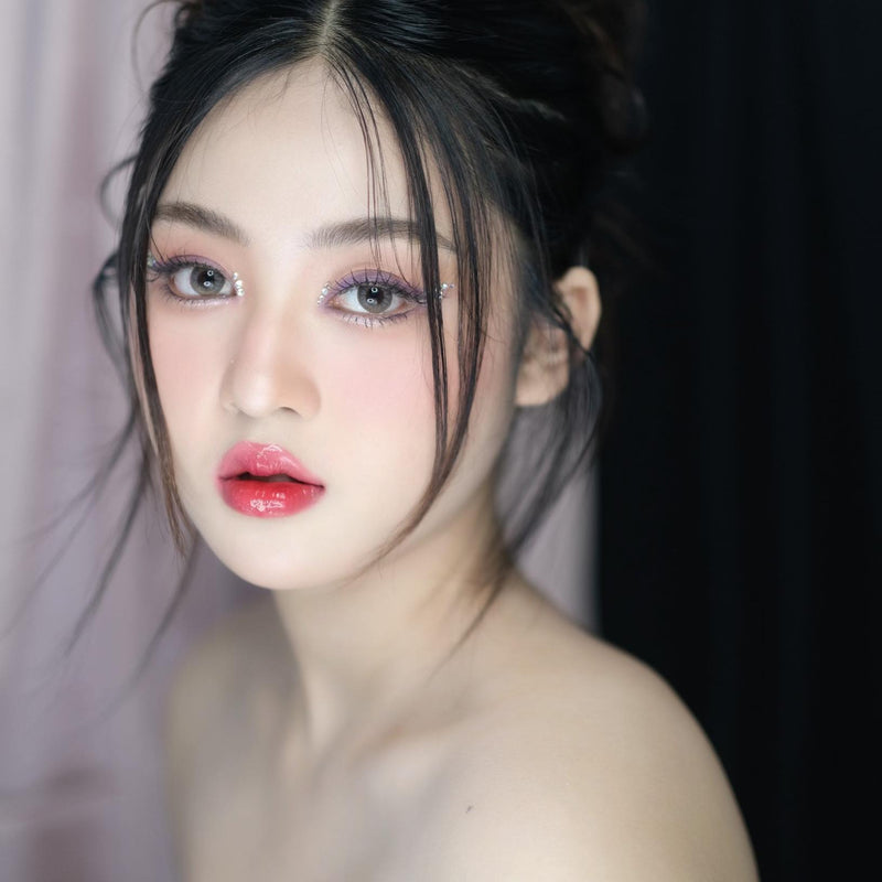 Close-up of a person with minimal makeup against a dark background