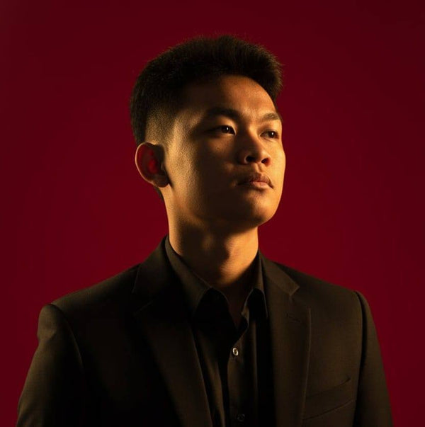 Man in a dark suit against a red background
