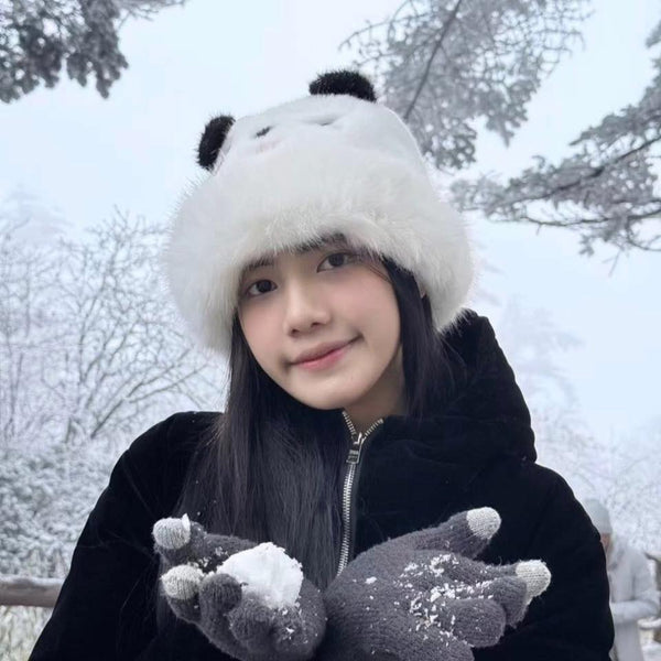 Person wearing a panda-themed hat and gloves in a snowy landscape