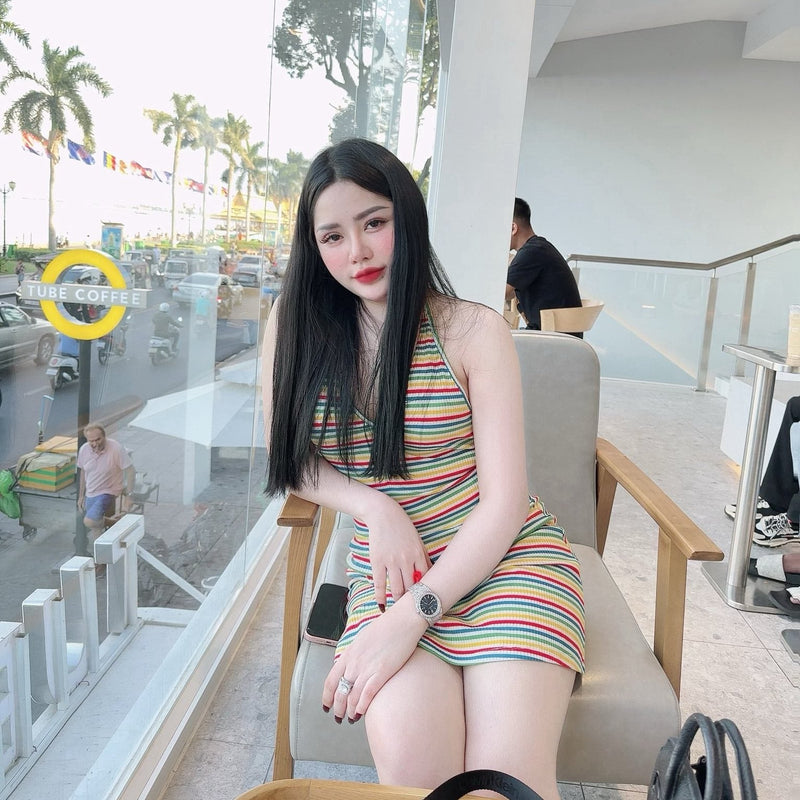 Woman in a colorful dress sitting on a chair with a city street in the background
