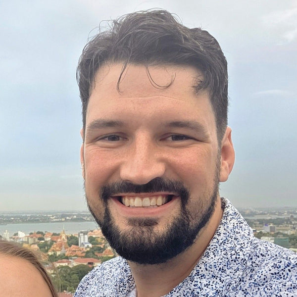 Man with a beard and mustache smiling with a scenic background