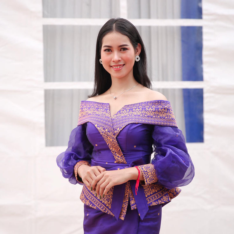 Woman wearing a traditional purple and gold dress with a white background
