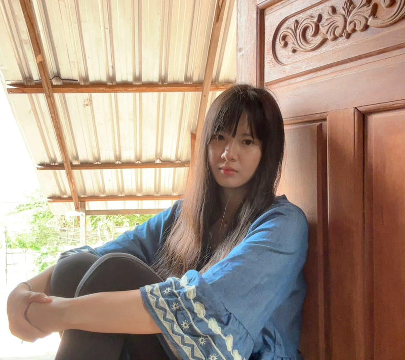 Woman sitting against a wooden wall with a natural light setting