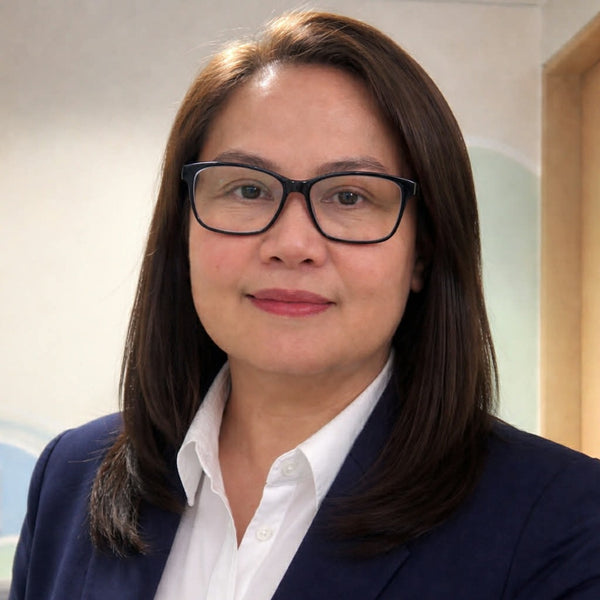 Woman wearing glasses and a dark blazer with a white shirt indoors.