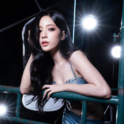 Woman sitting on a merry-go-round at night with bright lights in the background