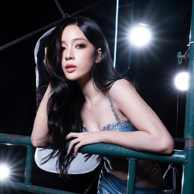 Woman sitting on a merry-go-round at night with bright lights in the background