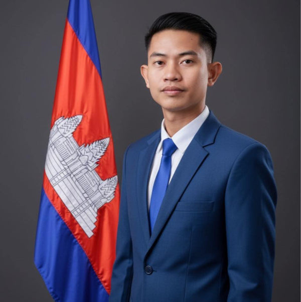 Man in a blue suit standing next to the Cambodian flag on a dark background