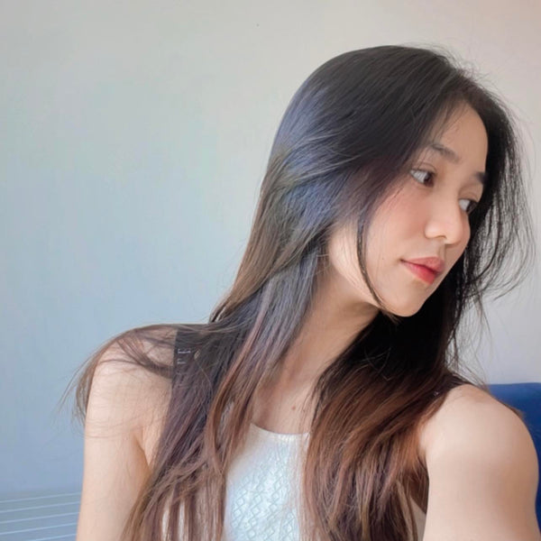 Woman with long dark hair looking to the side against a neutral background