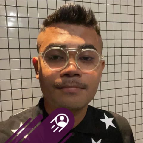 Person wearing round glasses in front of a tiled wall