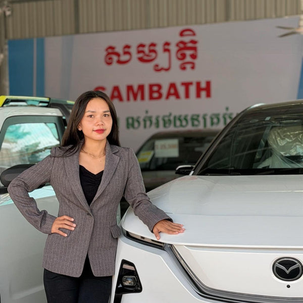 Woman standing next to a white car with a brand logo in the background