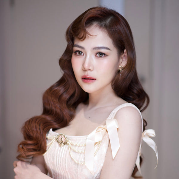 Woman with styled hair wearing a light-colored top with decorative elements.