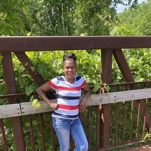 Woman standing on a wooden bridge with greenery in the background
