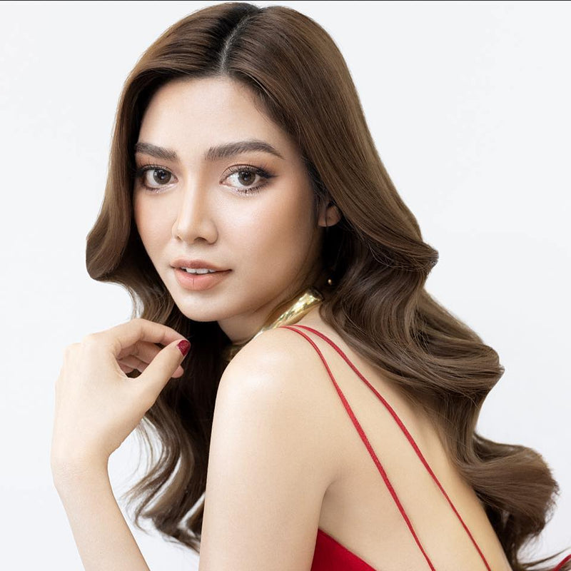 Woman with long, wavy hair wearing a red dress against a white background
